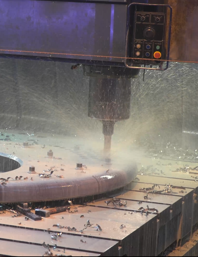 a machine drillikng a hole with metal working fluid spraying all over 